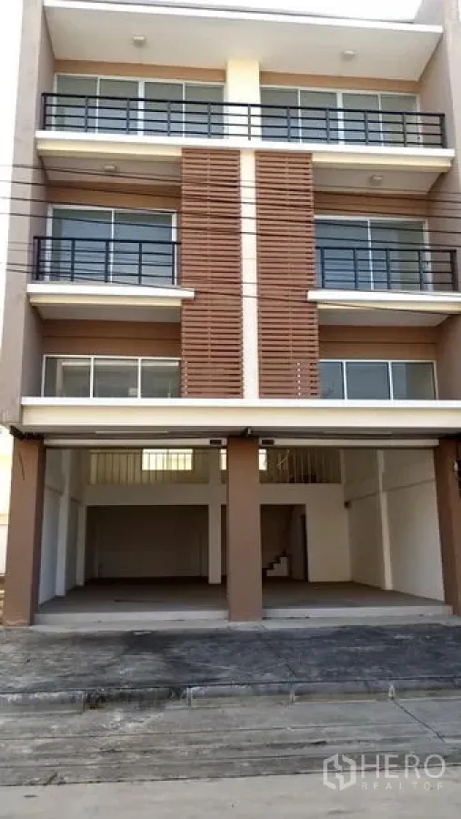 Office Space for sale in Khlong Luang, Pathum Thani - Front elevation of a four‑storey office building showing open double‑bay carport, glass‑railed balconies and louvered facade.