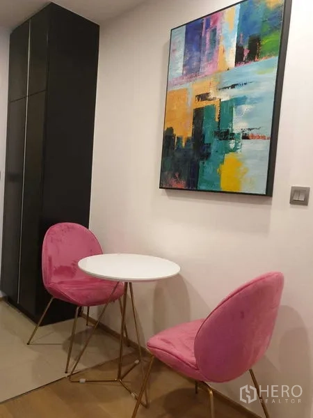 公寓 出租在Bang Rak, Bangkok - 小型用餐角，粉色绒面椅与抽象画