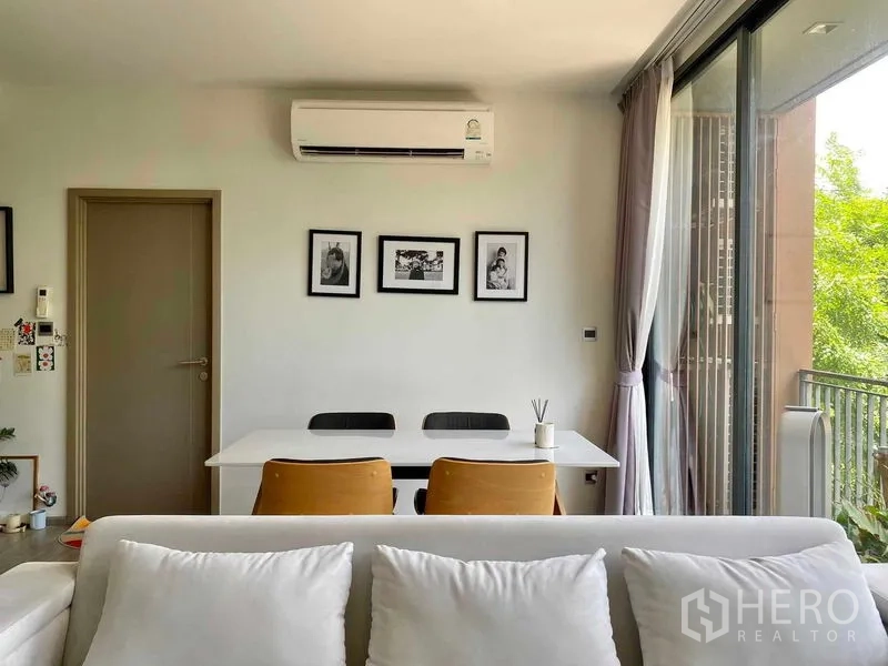 คอนโด ขายในWatthana, Bangkok - มุมรับประทานอาหารโต๊ะสีขาว มีรูปแขวนและแอร์แขวนผนัง ติดประตูกระจกเลื่อนไปยังระเบียงวิวต้นไม้