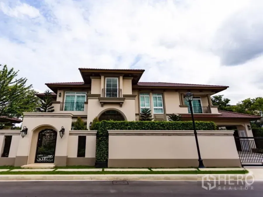 บ้าน ให้เช่าในMueang Samut Prakan, Samut Prakan - บ้านเดี่ยวสองชั้นสไตล์เมดิเตอร์เรเนียน กำแพงสูง ประตูเหล็ก และแนวพุ่มไม้ตัดแต่งริมถนนเงียบสงบ