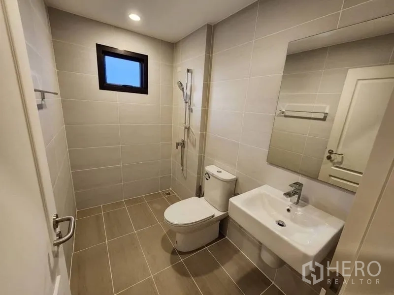 Detached House for rent in Prawet, Bangkok - Modern bathroom with walk-in shower, toilet and basin, finished in beige tiles.