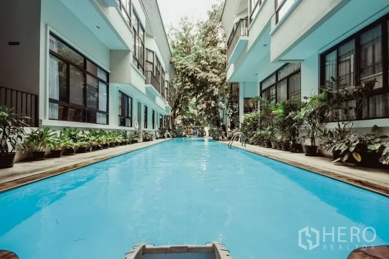 บ้าน ให้เช่าในKhlong Toei, Bangkok - สระว่ายน้ำส่วนกลางรูปทรงยาว รายล้อมด้วยต้นไม้ ระหว่างอาคารโลว์ไรส์.