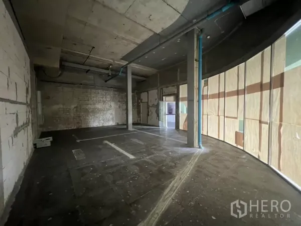 พื้นที่ขายปลีก ให้เช่าในSuan Luang, Bangkok - ภายในสภาพเปล่าพร้อมตกแต่ง เพดานเปลือย เสากลาง และแนวกระจกโค้งที่ปิดด้วยกระดาษ