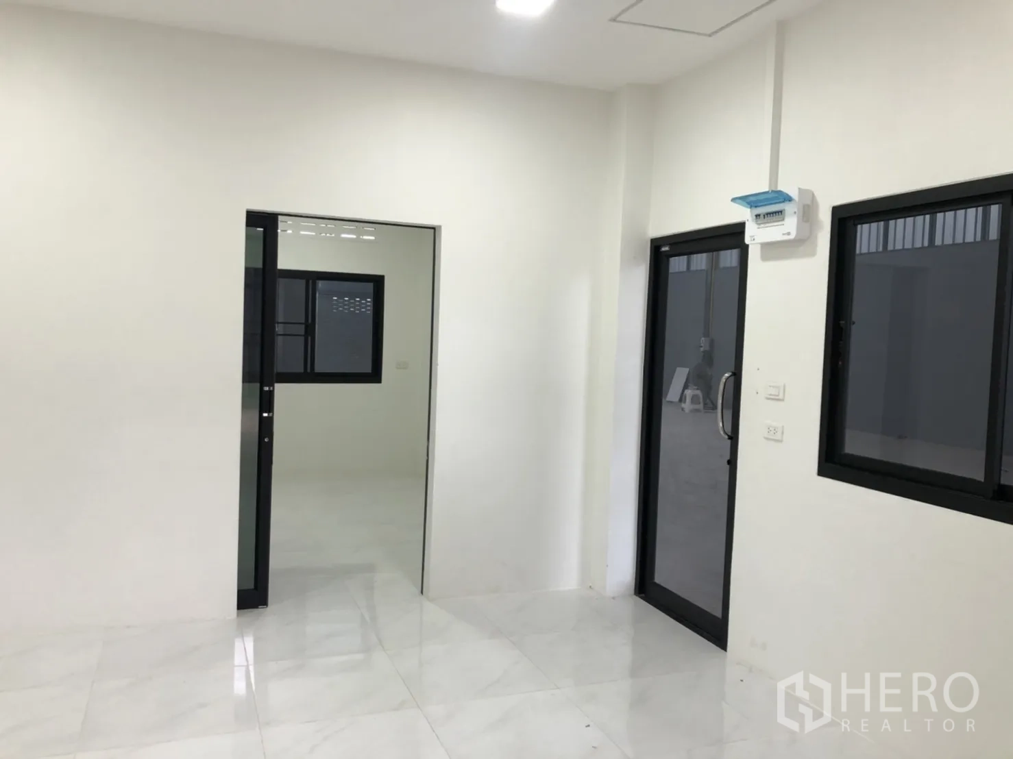 คลังสินค้า ให้เช่าในLam Luk Ka, Pathum Thani - ห้องทำงานสว่าง ผนังสีขาว หน้าต่างกรอบดำ และประตูกระจกเปิดสู่พื้นโกดัง