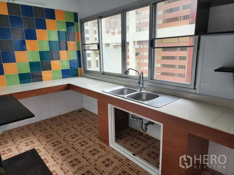 店屋 出租在Khlong Toei, Bangkok - 厨房带双水槽、长操作台和彩色瓷砖墙，临窗采光好。