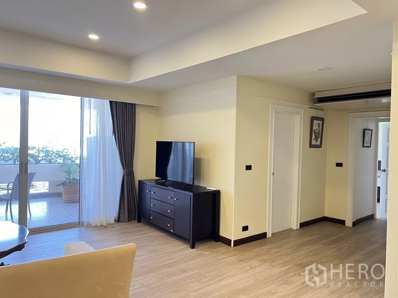 คอนโด ให้เช่าในKhlong Toei, Bangkok - พื้นที่นั่งเล่นแบบเปิด ไฟดาวน์ไลต์ พื้นไม้ และทางออกสู่ระเบียงขนาดใหญ่ข้างตู้ทีวี