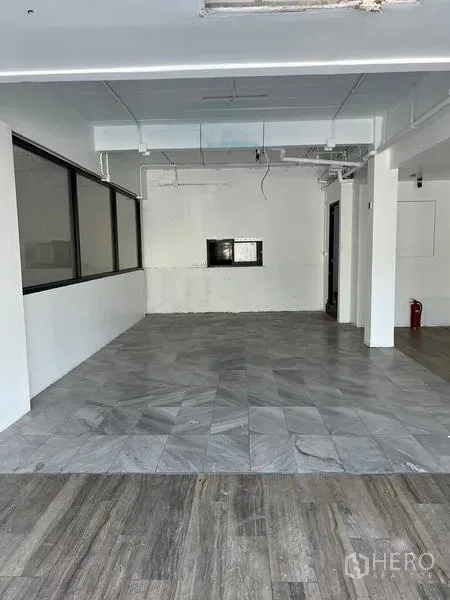 店屋 出租在Wang Thonglang, Bangkok - 中央空间宽敞，灰色地砖、白墙与顶置风管，适合设置吧台。