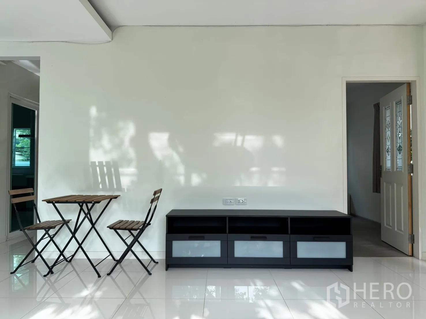 Detached House for rent in Bang Phli, Samut Prakan - Living area wall with small bistro table set and low TV cabinet.