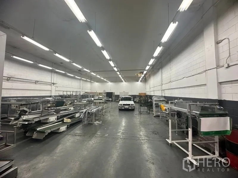 Factory for rent or sale in Khlong Luang, Pathum Thani - Spacious production hall with high ceiling, bright strip lighting and concrete floor.