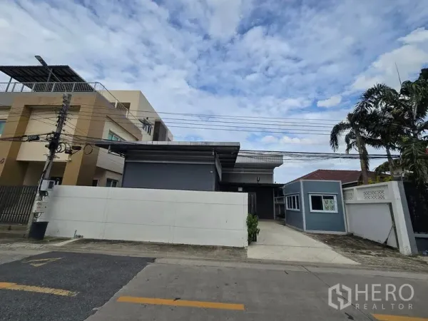 Warehouse for rent in Don Mueang, Bangkok - Street view of a modern gray warehouse compound in Don Mueang with secure wall and driveway.