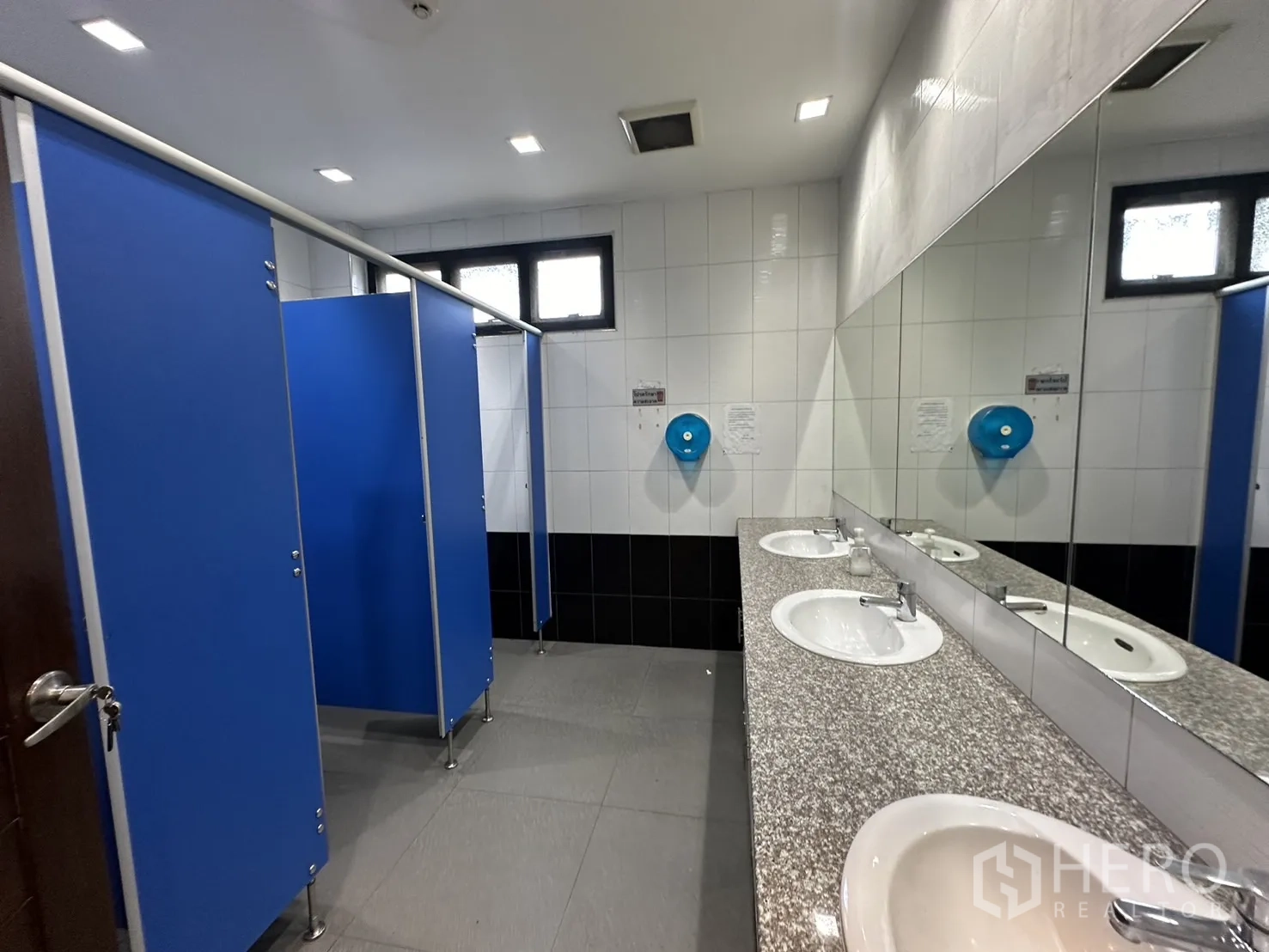Home Office for rent in Prawet, Bangkok - Restroom with long granite vanity, mirrors and blue cubicles.