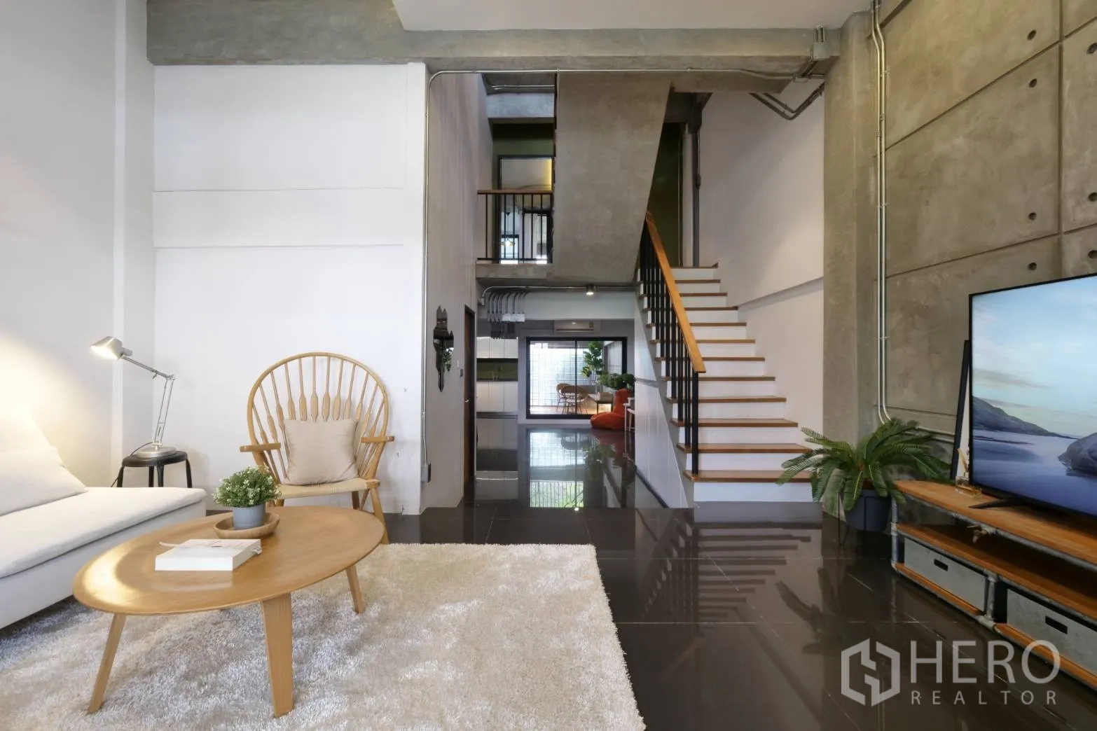 Townhouse for rent in Khlong Toei, Bangkok - Living room toward stairs with glossy tiles and media console.