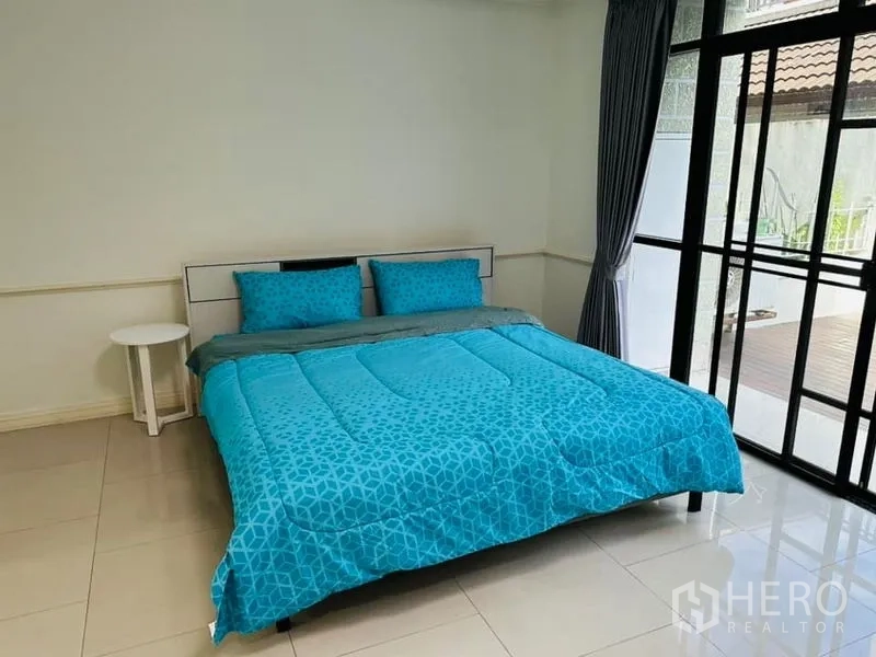 Home Office for rent in Watthana, Bangkok - Guest bedroom with teal bedding beside floor-to-ceiling sliding doors to a deck.