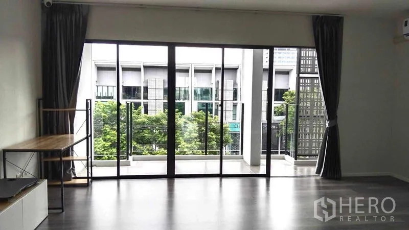 Home Office for rent - Large living area with full-height sliding glass doors opening to a balcony with greenery view.