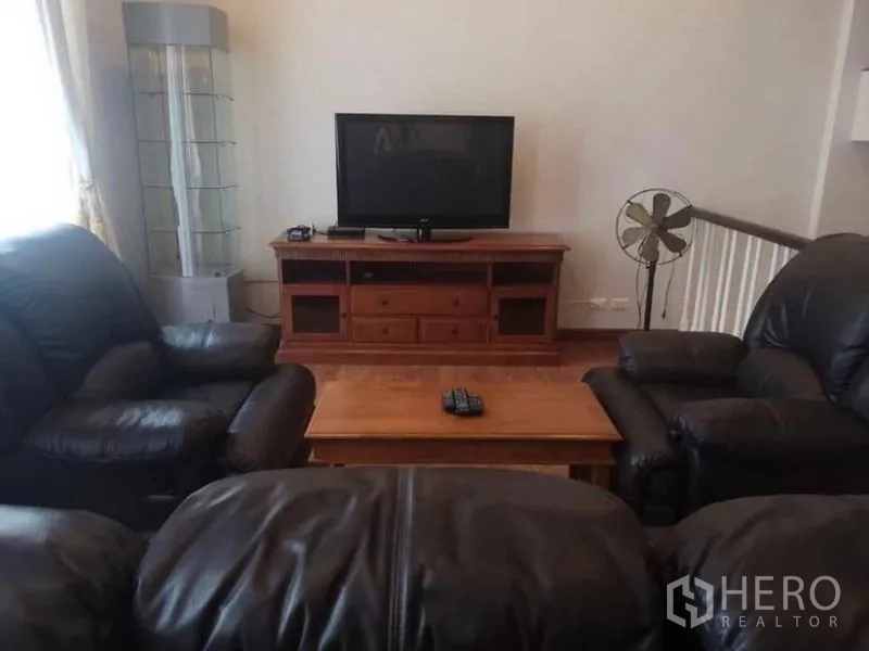 Detached House for rent in Wang Thonglang, Bangkok - TV corner with wooden media console, coffee table, and black leather sofas.