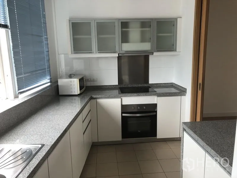 คอนโด ให้เช่าในKhlong Toei, Bangkok - ครัวปิด เคาน์เตอร์หินแกรนิตรูปตัวแอล ตู้บานกระจก และเตาอบบิลท์อิน