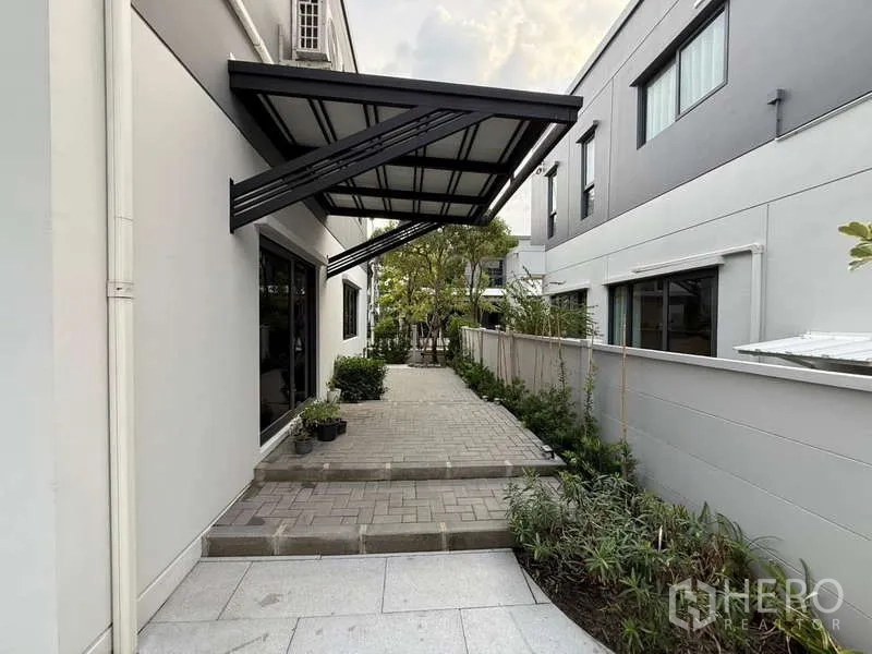 Detached House for sale in Bang Phli, Samut Prakan - Side patio with metal awning and steps leading to a landscaped garden.