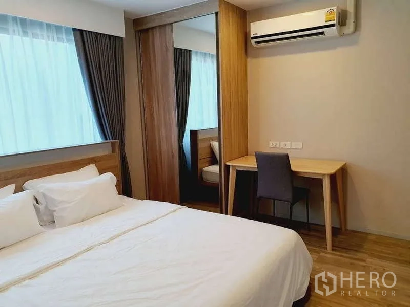 Condominium for rent in Sathon, Bangkok - Bedroom desk beneath air conditioner next to sliding-door wardrobe.