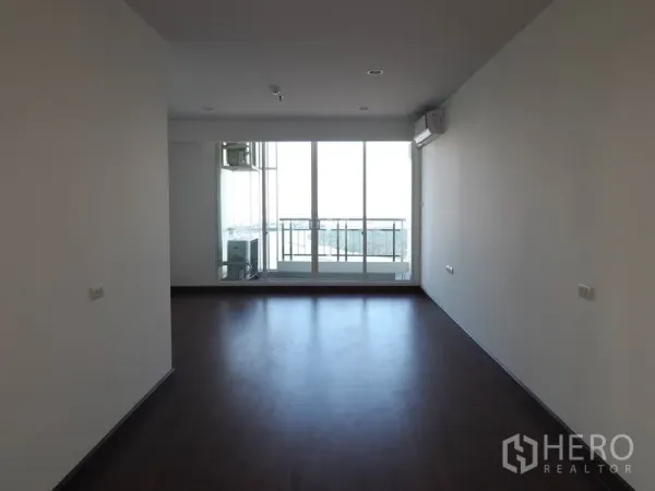 Condominium for rent in Yan Nawa, Bangkok - Bright bedroom with dark wood flooring, air conditioning and sliding glass doors to a balcony with skyline view.