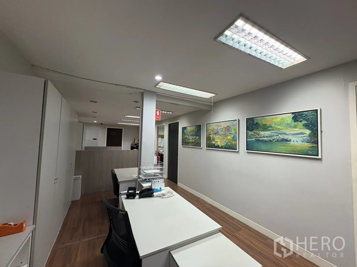 Factory for sale in Khlong Toei, Bangkok - Reception corridor with desks and framed artwork on the wall