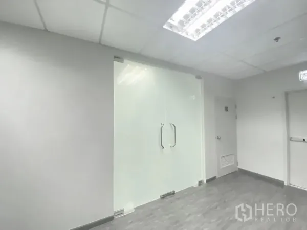 办公空间 出租在Chatuchak, Bangkok - 现代办公入口的磨砂玻璃双开门，金属把手与格栅天花灯。