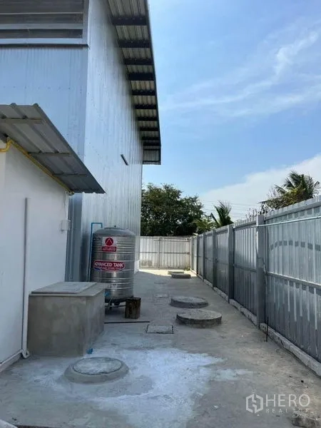Warehouse for rent in Nonthaburi - Rear service area showing stainless water tank, utility access points and perimeter fencing.