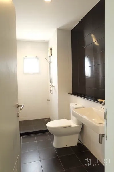 Home Office for rent in Wang Thonglang, Bangkok - Modern bathroom with walk-in shower, dark feature wall tiles and white fixtures.