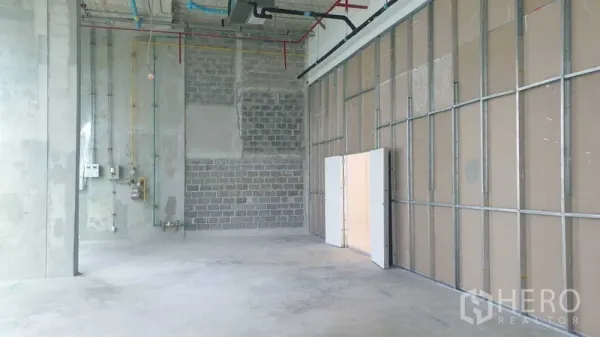 零售空间 出租 - 开阔的零售毛坯区，隔墙龙骨、挑高天花与水泥地面。