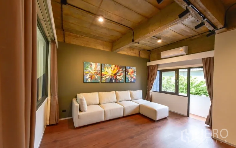 Home Office for rent or sale - Cozy living room with L-shaped sofa, colorful art and large windows.