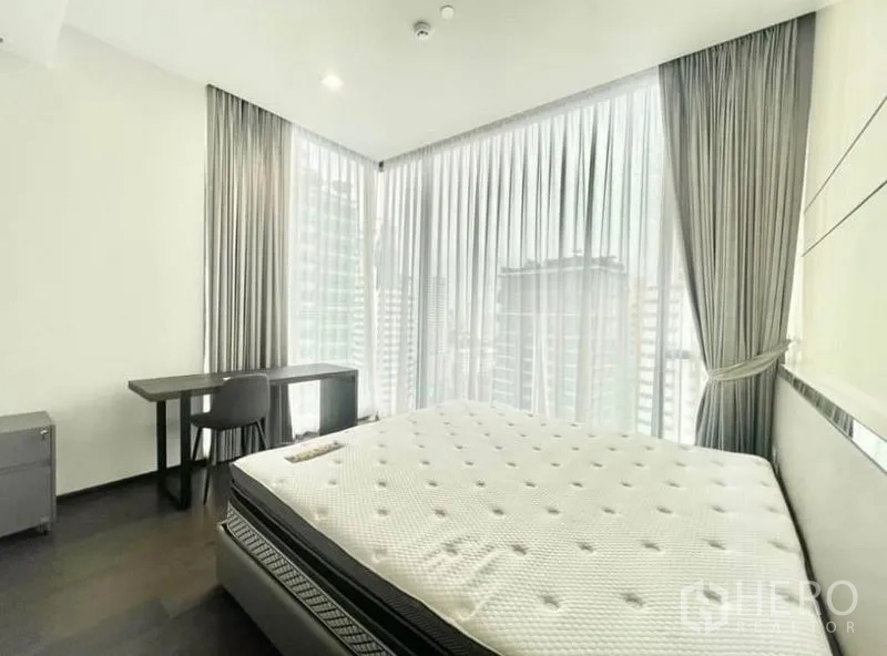 Condominium for rent in Watthana, Bangkok - Corner bedroom with large windows, city view, desk and queen-size bed.