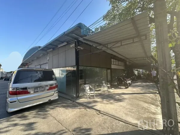 Warehouse for rent in Saphan Sung, Bangkok - Side view of the warehouse showing a covered loading awning and off-street parking.
