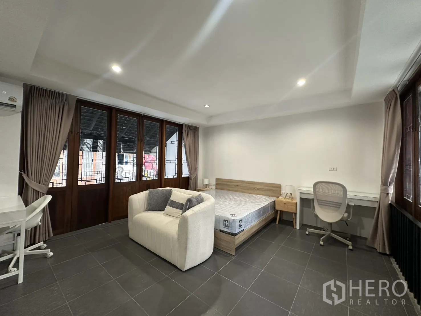 Apartment for rent in Pathum Wan, Bangkok - Bedroom opening to a balcony, featuring a bed, desk, and lounge chair.