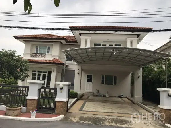 独立式住宅 出租在Phra Khanong, Bangkok - 两层独栋别墅正面，红瓦屋顶，带门禁与遮雨车棚。