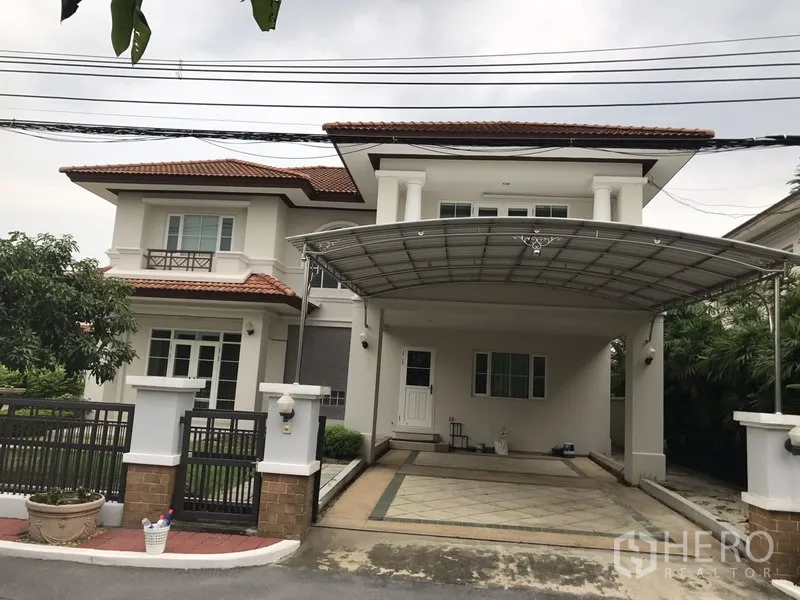 独立式住宅 出租在Phra Khanong, Bangkok - 两层独栋别墅正面，红瓦屋顶，带门禁与遮雨车棚。