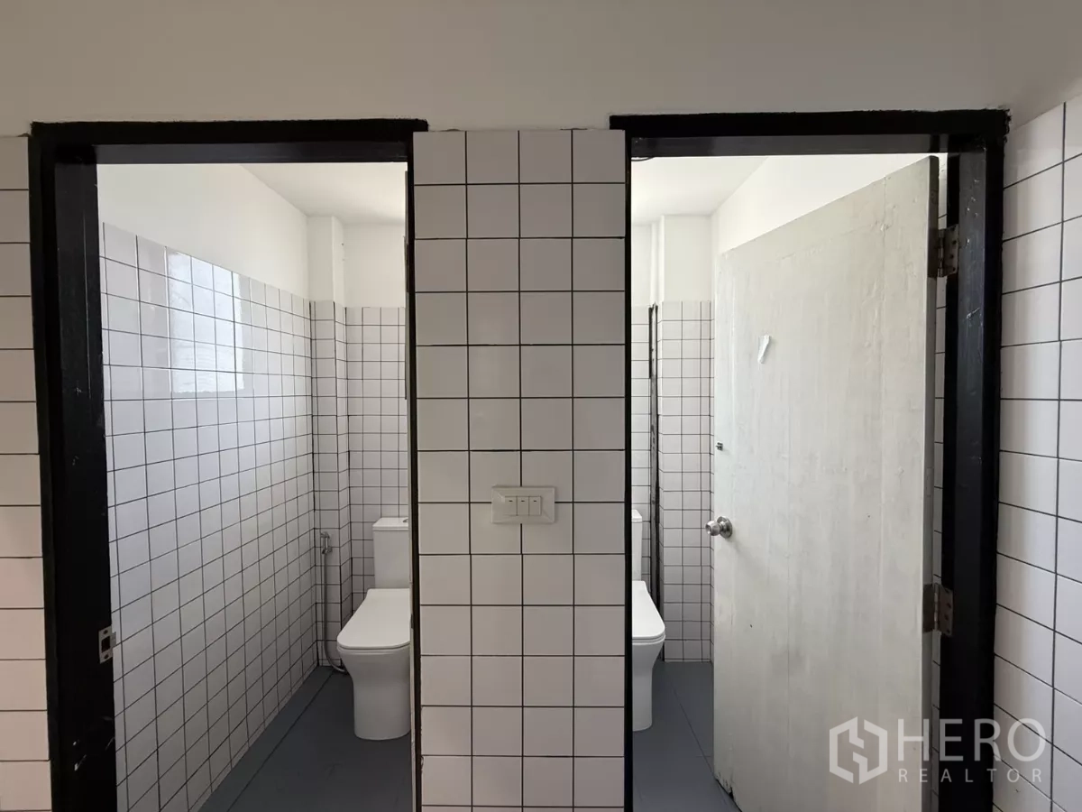 Office Space for rent in Wang Thonglang, Bangkok - Clean tiled restrooms with white square tiles and modern toilets inside the office.