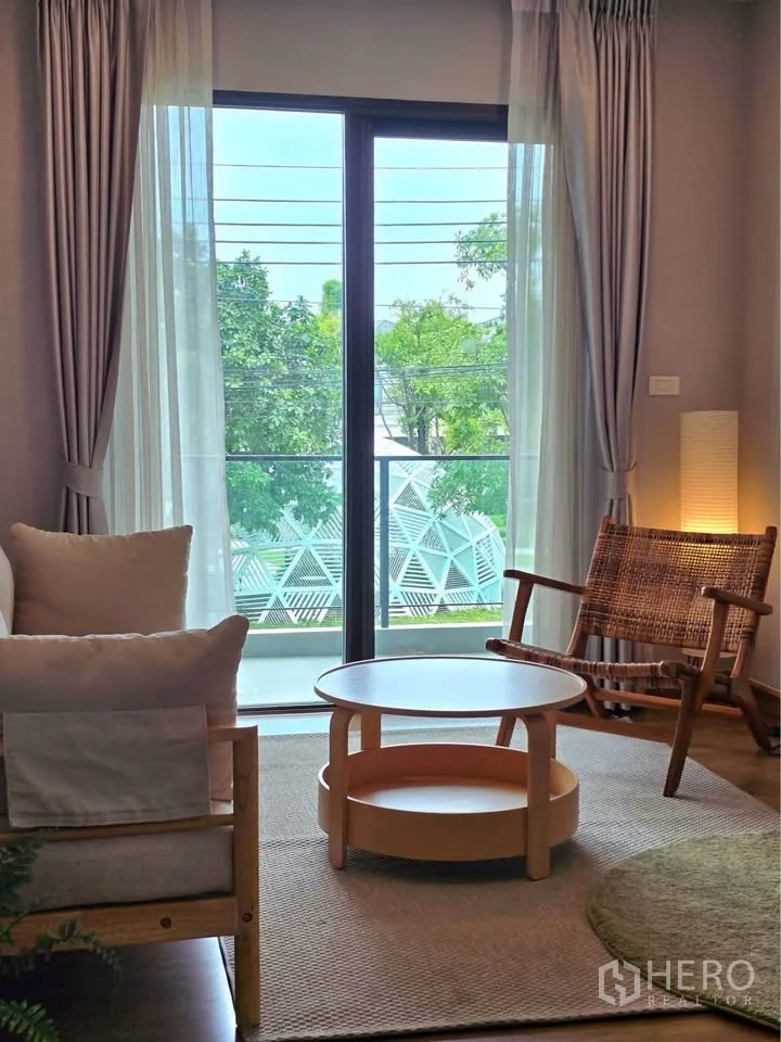 บ้านเดี่ยว for rent or sale in Bang Phli, Samut Prakan - มุมนั่งเล่นเปิดออกสู่ระเบียงด้วยประตูกระจกบานเลื่อน มองเห็นต้นไม้สีเขียว