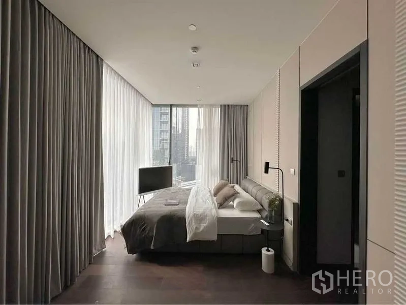 Condominium for rent or sale in Watthana, Bangkok - Spacious bedroom with two walls of windows, freestanding TV stand and skyline outlook.