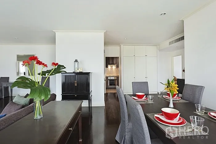 Condominium for rent in Khlong San, Bangkok - Close-up of dining area with table setting, looking toward the kitchen and storage cabinets.