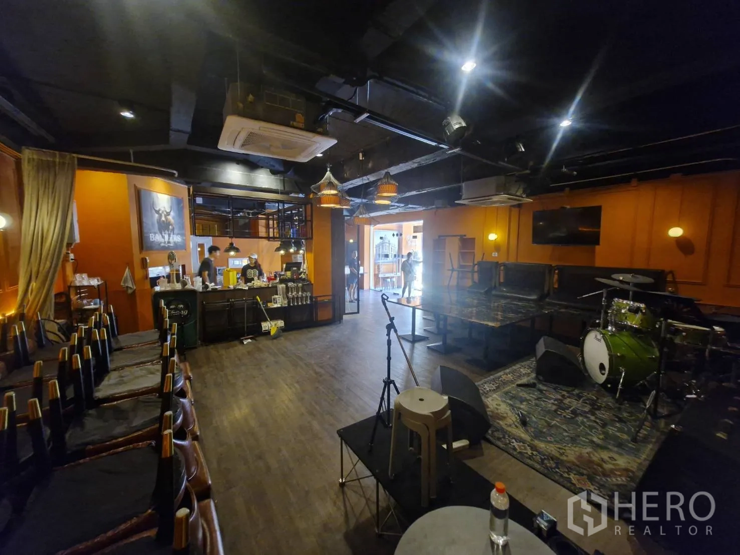 Shophouse for rent in Pathum Wan, Bangkok - Spacious dining area with stage, dark exposed ceiling, wood floors, and service bar.