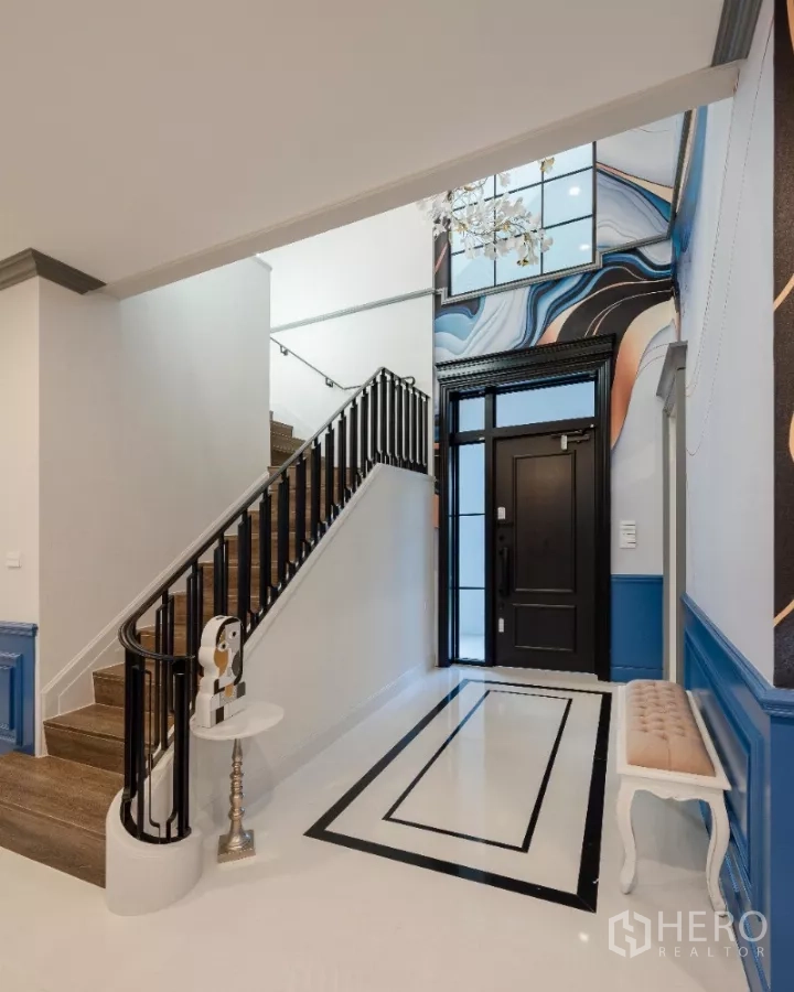 Detached House for rent or sale in Khlong Toei, Bangkok - Entrance foyer with black front door, staircase and abstract wall art.