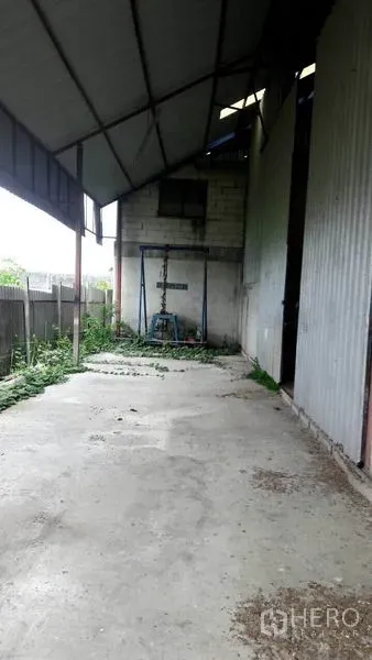 货栈 出售在Pathum Thani - 仓库侧边有顶装卸区，混凝土地面，临金属墙与围栏。