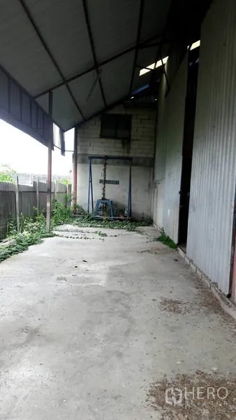 货栈 出售在Pathum Thani - 仓库侧边有顶装卸区，混凝土地面，临金属墙与围栏。