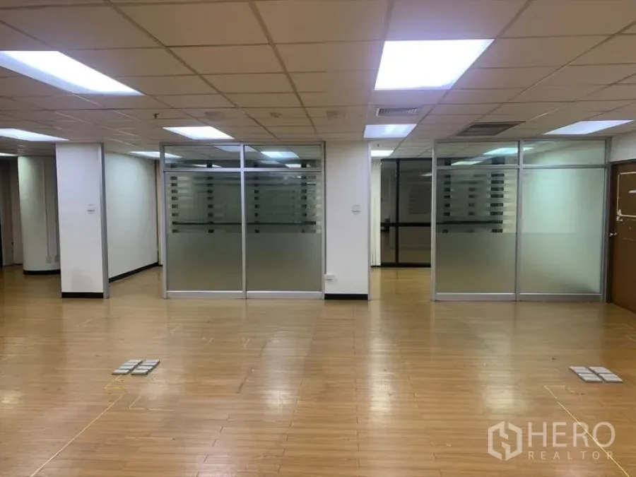 办公空间 出租在Bang Rak, Bangkok - 开放式办公室，木地板、吊顶灯和磨砂玻璃隔间。