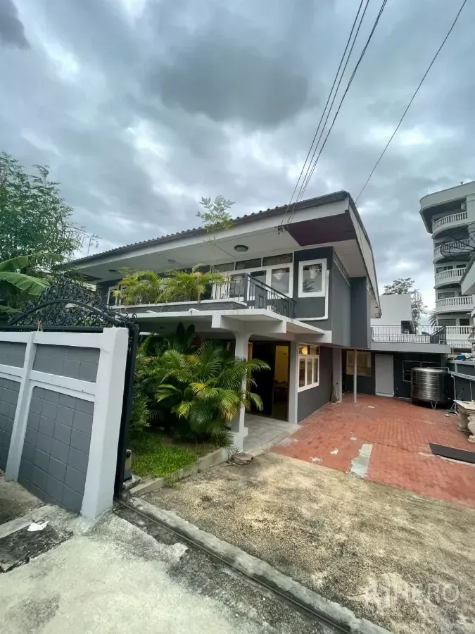 独立式住宅 出租在Watthana, Bangkok - 灰色双层独栋别墅外观，带大门入口、红砖车道与葱郁绿植。