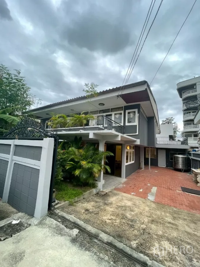 独立式住宅 出租在Watthana, Bangkok - 灰色双层独栋别墅外观，带大门入口、红砖车道与葱郁绿植。