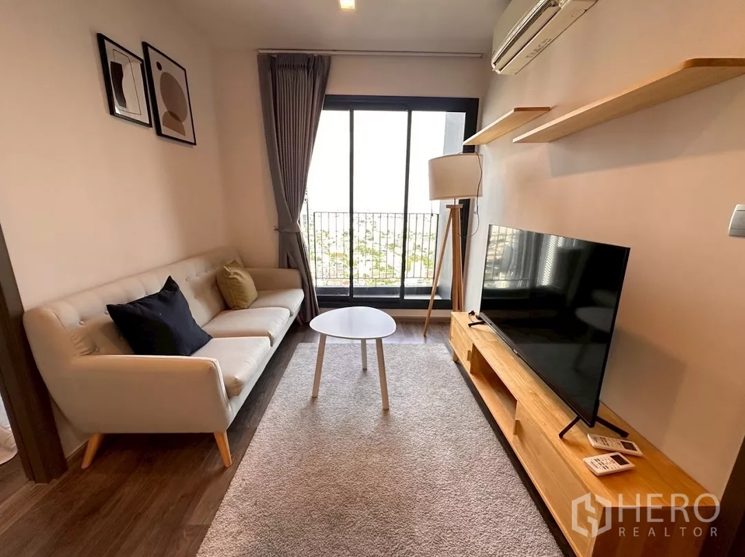 Condominium for rent in Chatuchak, Bangkok - Bright living room with cream sofa, TV console and balcony at Life Ladprao Valley.