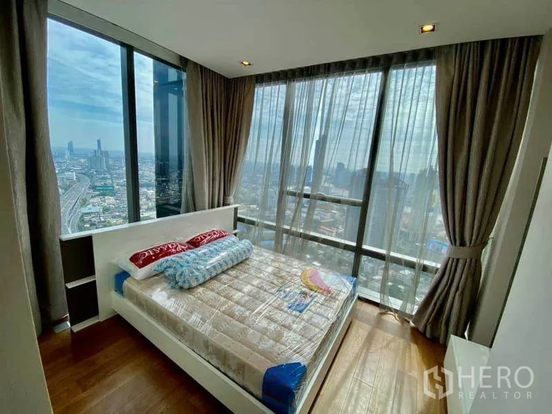 Condominium for rent in Sathon, Bangkok - Corner bedroom with floor-to-ceiling windows, sheer curtains and panoramic city views.