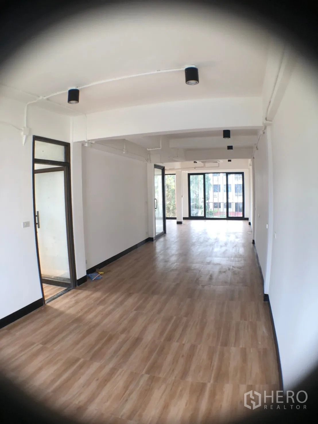 带办公室的家 出租在Phra Khanong, Bangkok - 狭长开放式办公层，木纹地砖、白墙与推拉玻璃门。