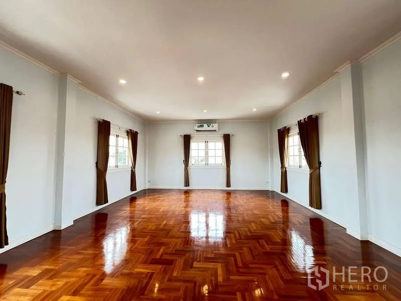 Detached House for rent in Bang Phli, Samut Prakan - Expansive multipurpose room with glossy herringbone wood flooring and windows on three sides.