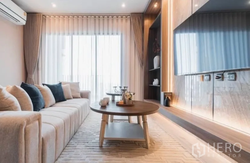 คอนโด for rent in Watthana, Bangkok - ห้องนั่งเล่นมีโซฟาตัวยาว โต๊ะกาแฟ และผนังทีวี ข้างประตูกระจกระเบียง